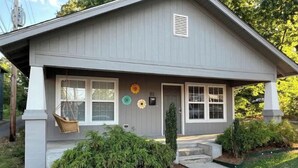 A single-story house with a front porch, a swing chair, and a mailbox.