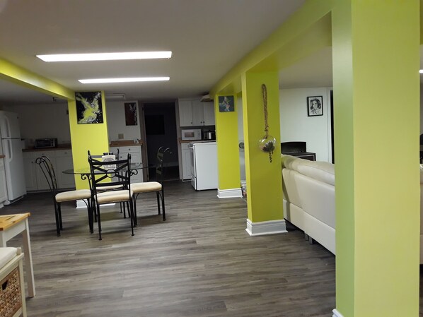 Una cocina moderna con armarios blancos, una mesa de comedor con sillas y una pared de color amarillo brillante.