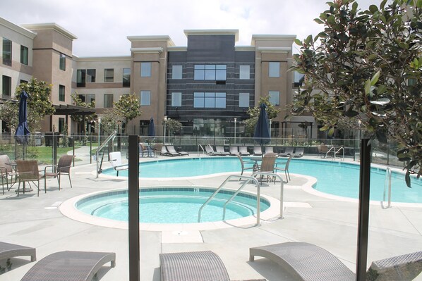 A pool area with lounge chairs and a clear view of the building in the background.