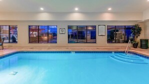 An indoor swimming pool with clear glass walls, a tiled floor, and a pool ladder. - Studio | Free Breakfast, Indoor Pool & Hot Tub (Davenport)