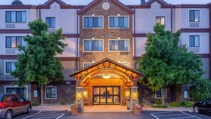 A multi-story hotel with a stone facade, large windows, and a central entrance with a decorative arch. - Studio | Free Breakfast, Indoor Pool & Hot Tub (Davenport)