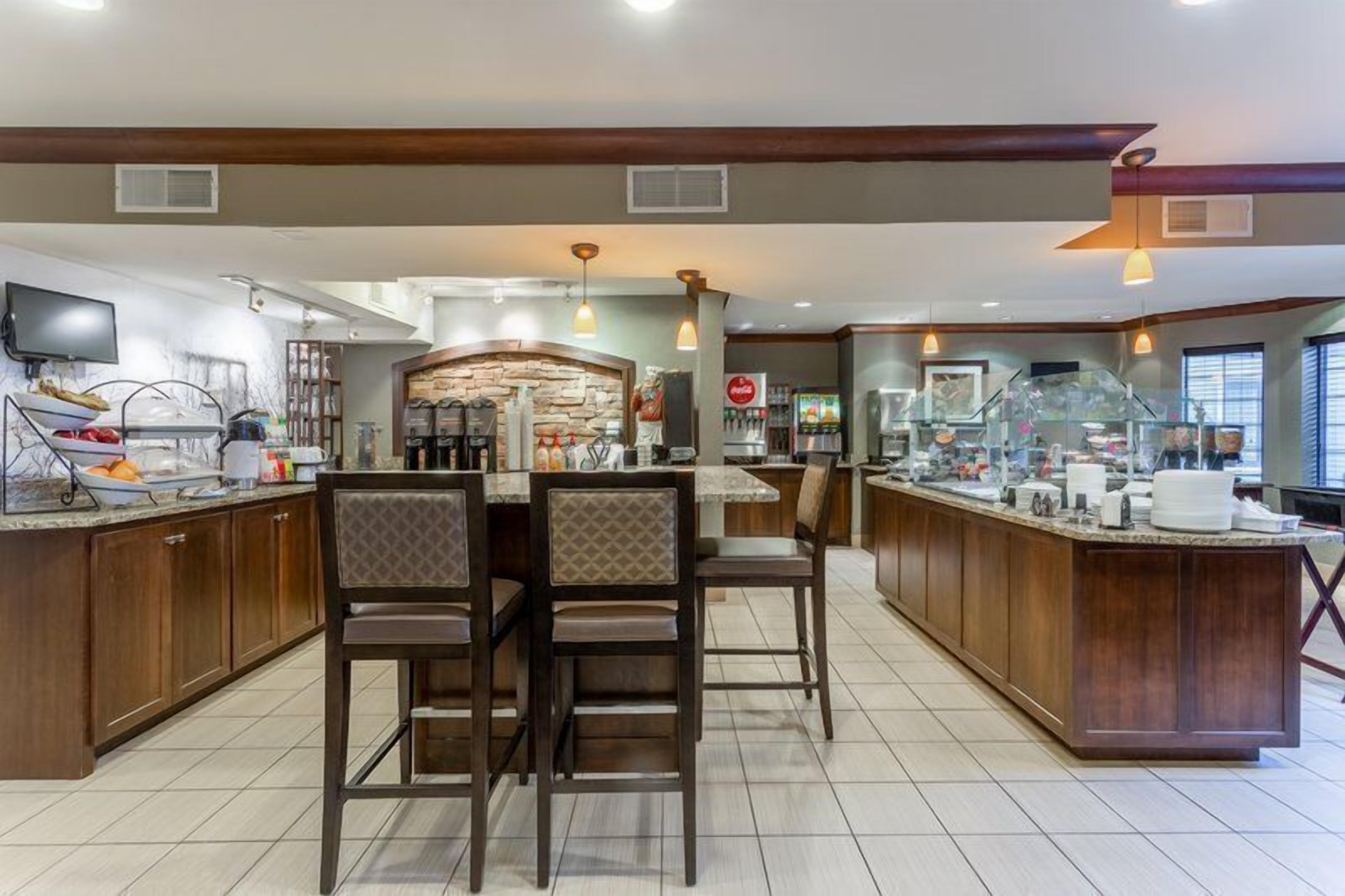 Uma cozinha moderna com ilha central, bancada para refeições rápidas e parede decorada com pedra.