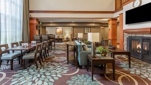 A hotel lobby with a dining area, seating, a fireplace, and a television. - Studio | Free Breakfast, Indoor Pool & Hot Tub (Davenport)
