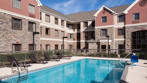A swimming pool with lounge chairs and a stone facade building.
