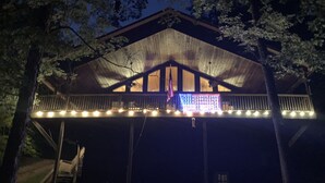 Una cabaña de madera con un porche cubierto y luces colgantes.