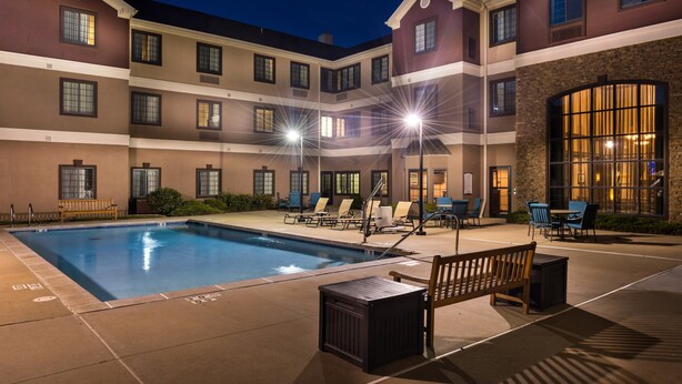 A hotel pool area with a rectangular pool, lounge chairs, and a wooden bench. - 1 Bedroom | Pool & Gym. Free Breakfast (O'Fallon)