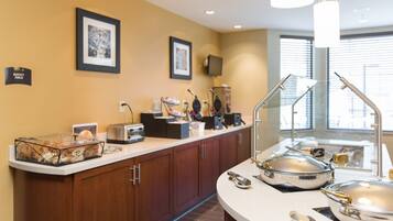 A modern kitchen with a buffet setup, including a glass display case, a toaster, and a sink with a glass partition.