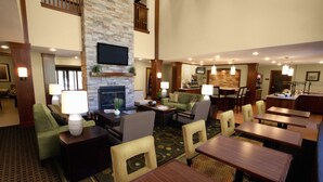 A hotel lobby with a fireplace, seating area, and a bar. - Free Wi-Fi, Free Breakfast + Indoor Pool (Auburn Hills)