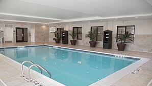 An indoor swimming pool with clear water, surrounded by potted plants and a tiled floor. - Free Wi-Fi, Free Breakfast + Indoor Pool (Auburn Hills)