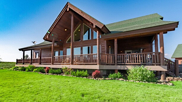 A large wooden cabin with a spacious deck and multiple windows.