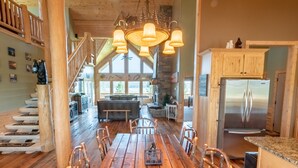 A spacious kitchen with a wooden dining table, chairs, and a stainless steel refrigerator.