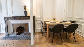 A dining area with a wooden table set for two, a fireplace, and a vase with dried plants. - Le Chavannes-Ecrin élégant & Cosy- Pentes X Rousse (Lyon)