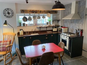 A kitchen with a red table, dark cabinets, and a gas stove.