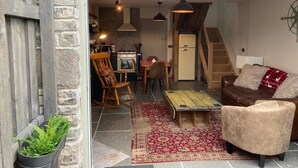 Un intérieur chaleureux avec un coin repas, un canapé et un escalier menant à l’étage.