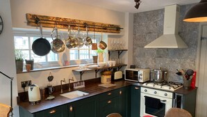 Une cuisine dotée d’un îlot central, d’une cuisinière, d’un four à micro-ondes et de casseroles suspendues.