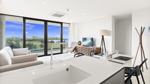 Una cocina moderna con una isla grande, un comedor con sillas, un televisor y vistas al exterior.