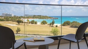 Habitación con vistas a una playa y al océano, que incluye dos sillas y una mesa con un libro.