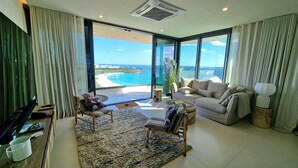 Ein modernes Wohnzimmer mit einem großen Fenster und Blick auf den Strand und den Ozean.