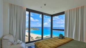 Ein Hotelzimmer mit großem Fenster und Blick auf Strand und Meer.