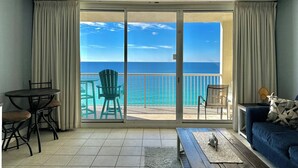 Quarto com vista para o oceano, ventilador de teto, mesa com cadeiras e um sofá.