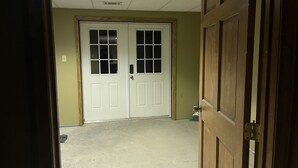 A hallway with a double door, a concrete floor, and a green wall. - Cozy 2 bedroom suite with private entrance and continental breakfast. (Port Matilda)