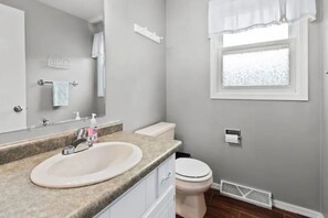 Een badkamer met een wastafel, toilet en raam.