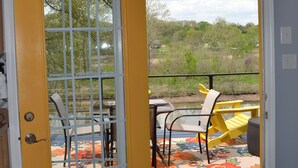 A yellow door leading to an outdoor patio with a table and chairs, a blue rug, and a view of trees and hills.