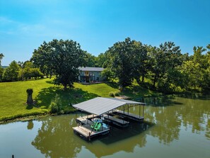 A lakeside property with a dock, a house, and lush greenery.