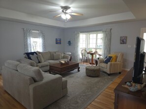 A living room with a sofa set, ottoman, coffee table, and a television. - Lakefront, private dock on cove near HaHa Tonka, Ballparks National Park, kayaks (Camdenton)
