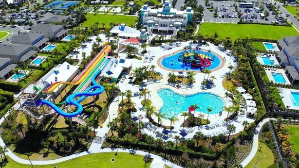 An aerial view of a resort with multiple swimming pools, a water park, and various resort buildings. - Fun and Stylish Family Villa in Encore Resort! (Kissimmee)