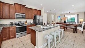A modern kitchen with granite countertops, stainless steel appliances, and wooden cabinets. - Fun and Stylish Family Villa in Encore Resort! (Kissimmee)
