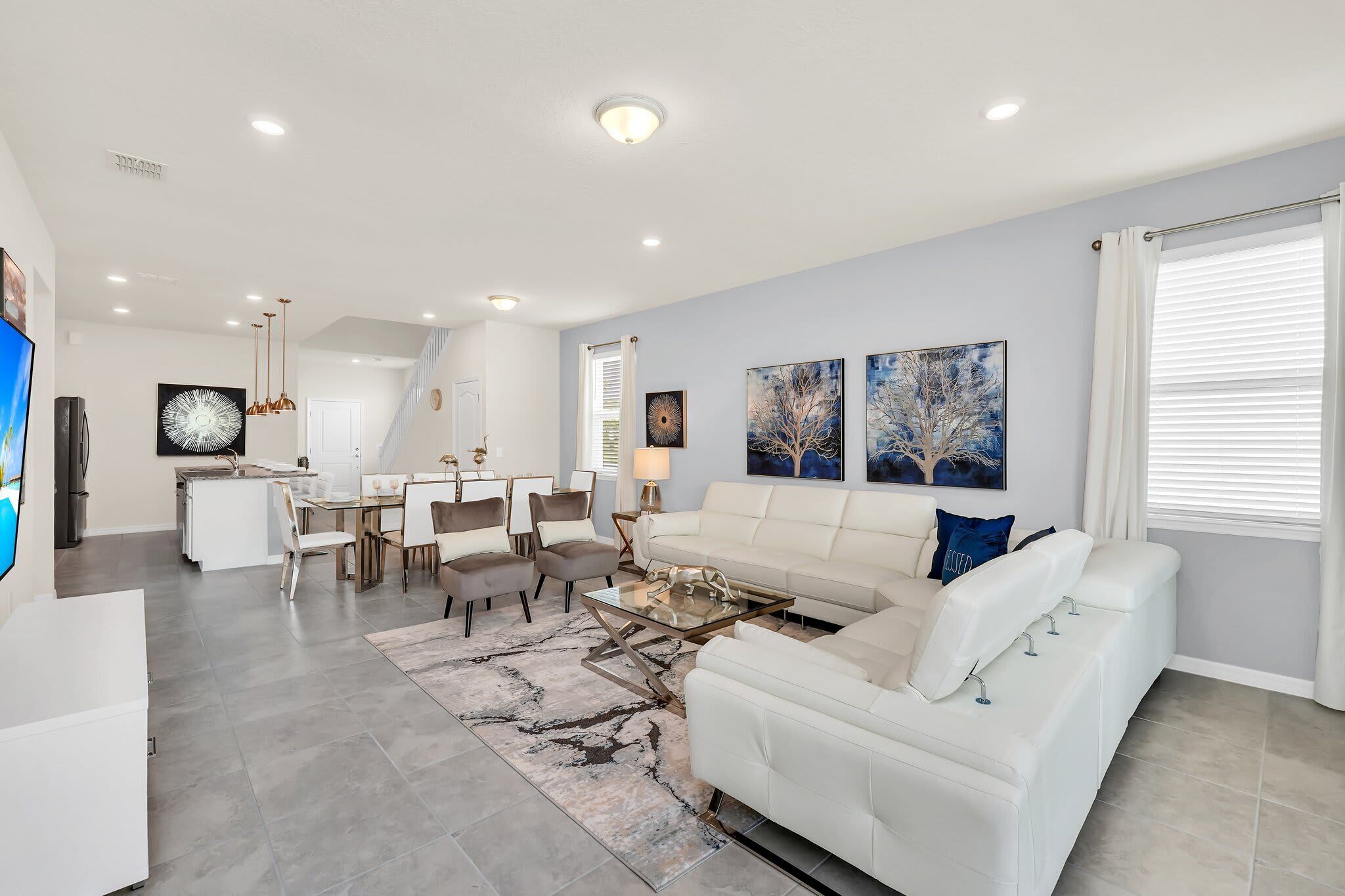 A modern living room with a white sofa, a glass coffee table, and a dining area with a white table and chairs.