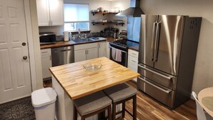 Een gezellige, compacte keuken met een houten keukeneiland, roestvrijstalen apparatuur en witte kasten.