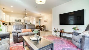 A modern living room with a grey sofa, a coffee table, and a TV mounted on the wall. - Mankato Getaway w/ Game Room & Salt Water Hot Tub! (Mankato)