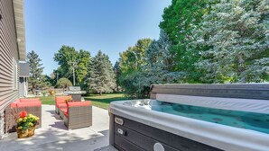 A hot tub with a wooden exterior, surrounded by wicker furniture and a concrete patio. - Mankato Getaway w/ Game Room & Salt Water Hot Tub! (Mankato)