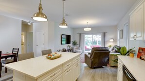 A modern kitchen with a central island, pendant lighting, and a dining area with a table and chairs. - Mankato Getaway w/ Game Room & Salt Water Hot Tub! (Mankato)