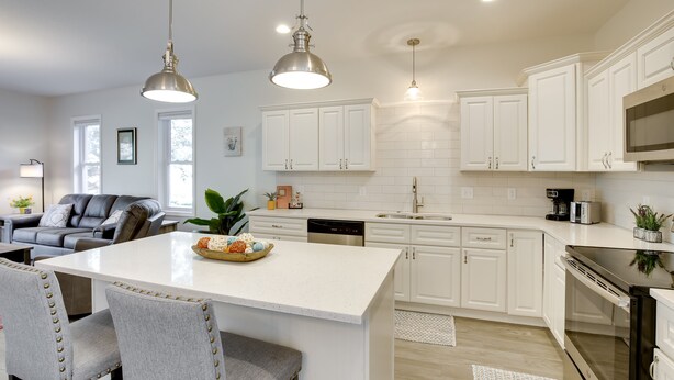 A modern kitchen with white cabinets, a central island, and pendant lighting. - Mankato Getaway w/ Game Room & Salt Water Hot Tub! (Mankato)