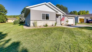 A single-story house with a garage, a well-maintained lawn, and an American flag. - Mankato Getaway w/ Game Room & Salt Water Hot Tub! (Mankato)