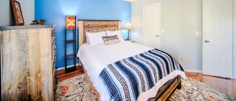 A bedroom with a bed, a ceiling fan, a dresser, and a nightstand.