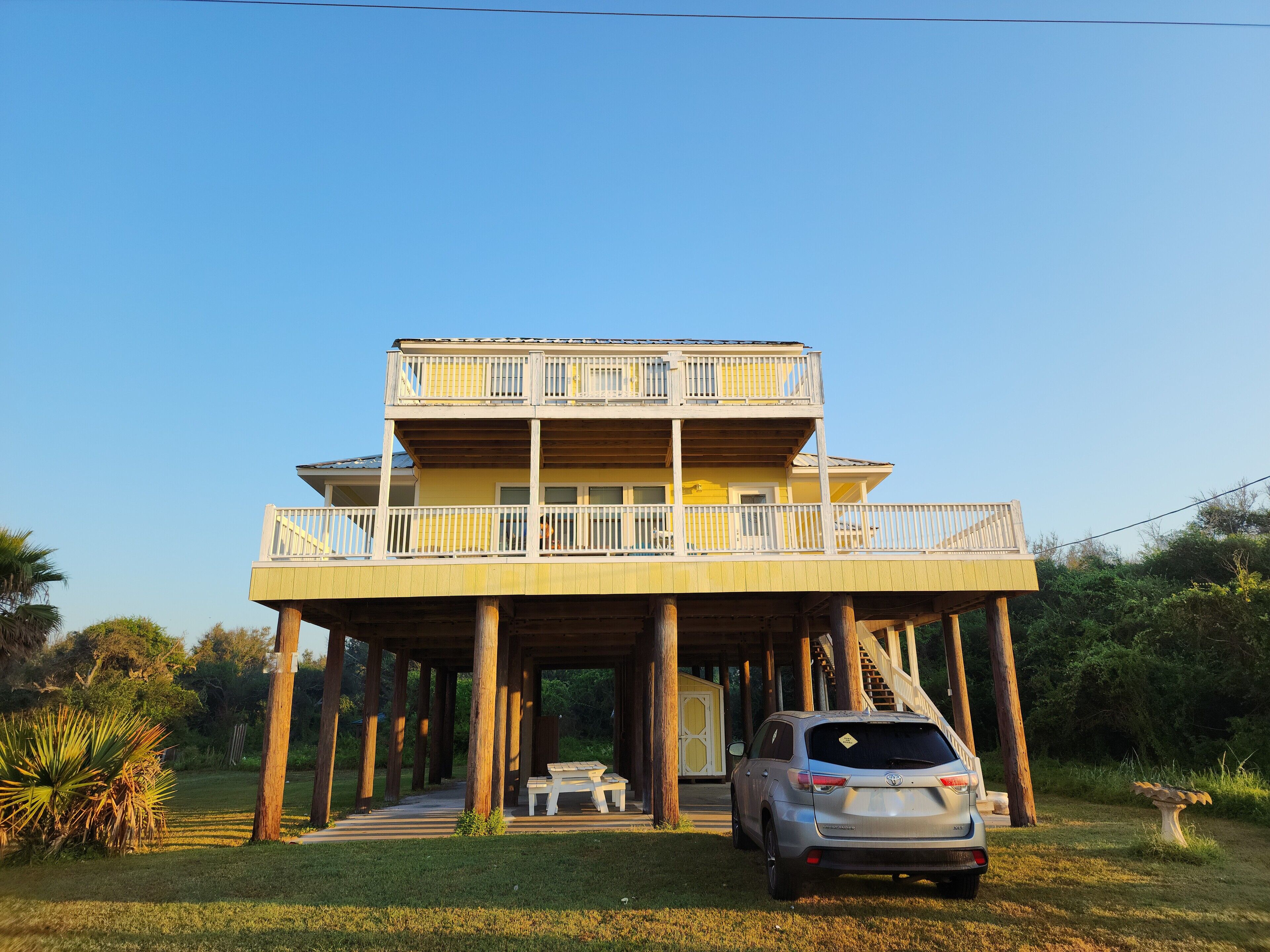 A two-story building with a balcony, a covered patio, and a car parked in front.