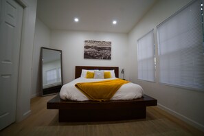 Cozy retreat with a central bed, nightstand, and lamp, featuring a framed landscape painting above.