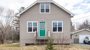 A two-story house with a green front door, a garage, and a small front yard.