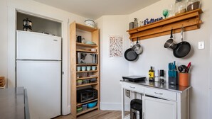 A compact kitchen with a white refrigerator, wooden shelves, a microwave, and a coffee maker.