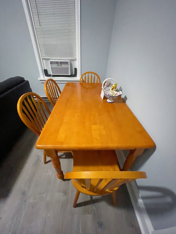 A dining area with a wooden table and four chairs. A basket with items is on the table.