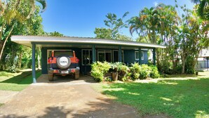 A single-story house with a covered porch and a parked SUV. - Cheerful Bungalow with pool! (Apia)