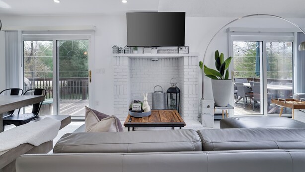 A modern living room with a fireplace, a flat-screen TV, and a dining area with a table and chairs.