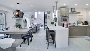 A modern kitchen with a central island, built-in appliances, and a dining area with a large window.