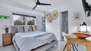 A bedroom with a bed, bedside tables, a desk, and a ceiling fan.