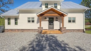 A two-story house with a front porch, a gravel driveway, and a metal roof. - 5 Star Cabin | Pet Friendly | Rushing Creek | Mountain Views | Foosball |Firepit (Cleveland)