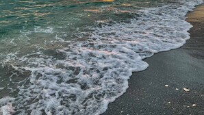 A beach with waves gently lapping onto the shore, a sunset in the background, and a person in a kayak. - Brand new Private Home-Beach Nearby in SW Florida (Port Charlotte)